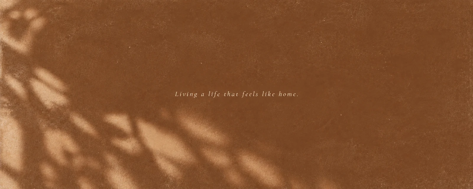 Sunlight and soft leaf shadows on a warm terracotta background; Living a life that feels like home